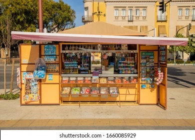 A mustard-coloured news stand in an open-air market in Seville